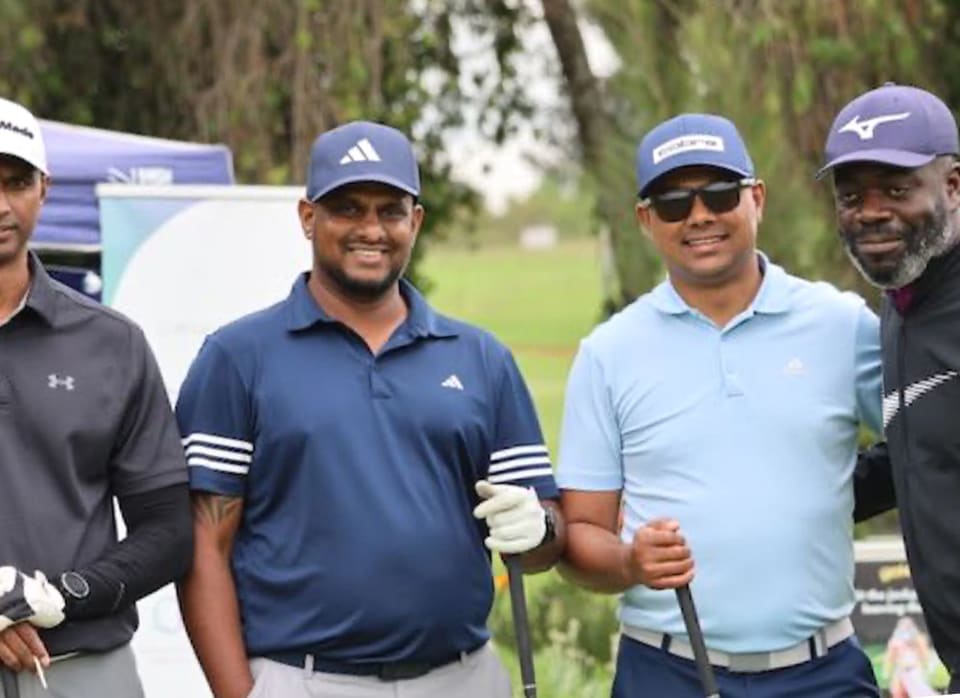 Four golfers in caps smiling on the course